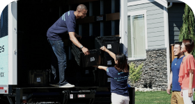 Movers loading black crates into a truck