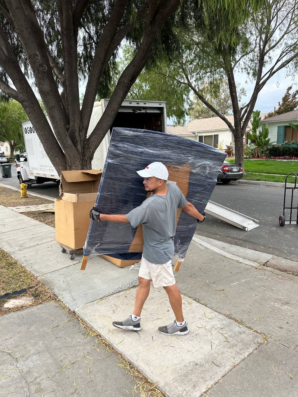 Mover carrying a wrapped mattress during a residential move
